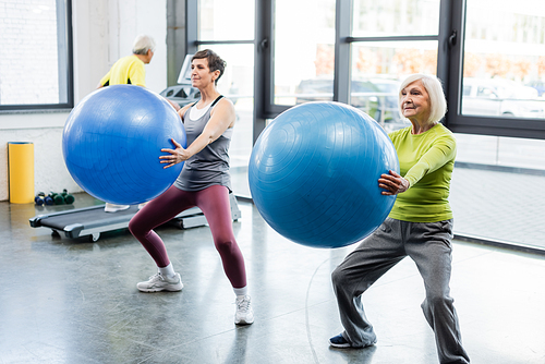 Elderly sportswomen exercising with fitness balls in gym
