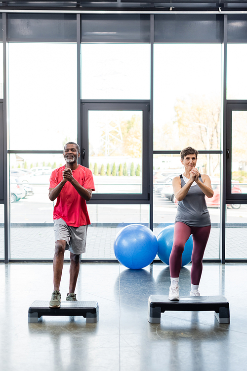 Senior interracial people training on aerobic steps in gym