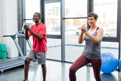 Interracial people training near sport equipment in gym