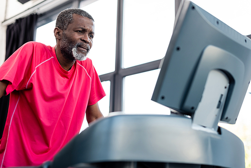 Focused african american sportsman training on blurred treadmill in gym