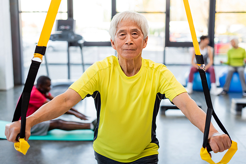 Elderly asian sportsman training with resistance band in sports center