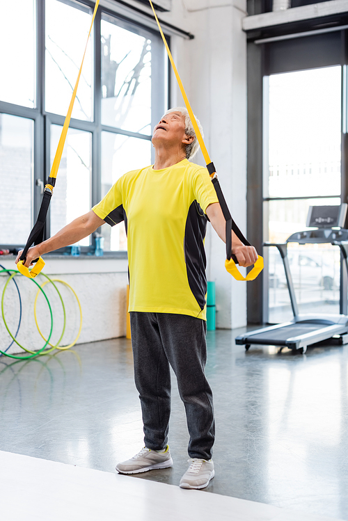 Elderly asian sportsman training with resistance band in gym