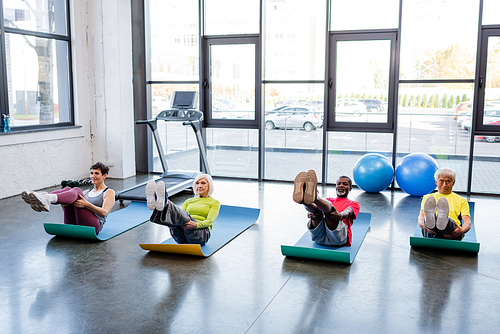 Multicultural people in sportswear training on fitness mats in gym