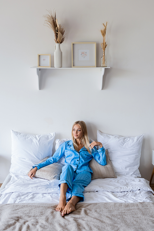 pleased young woman smiling while resting on bed at home