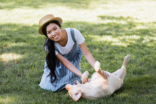 joyful asian woman  while having fun with labrador on lawn