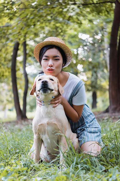 asian woman  while hugging labrador dog in park
