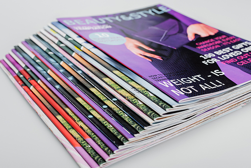 pile of beauty and style magazines on grey background, close up view