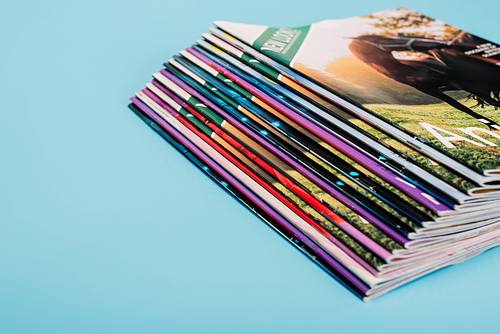 stack of colorful magazines collection isolated on blue