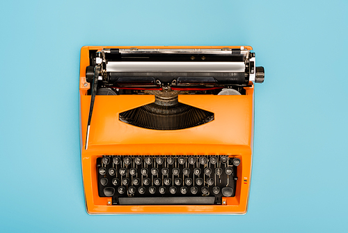 top view of orange typewriter with black keyboard isolated on blue