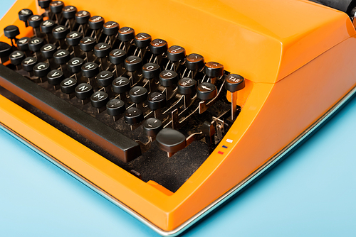 close up view of black keyboard of orange typewriter on blue