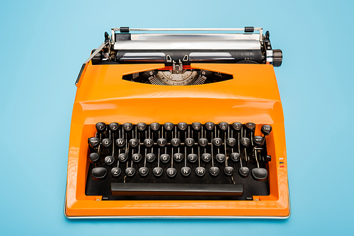 bright orange typewriter with black keyboard on blue background