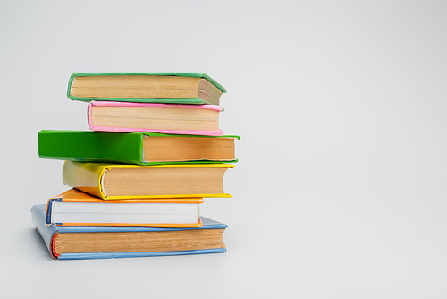 stacked books with multicolored covers on grey background