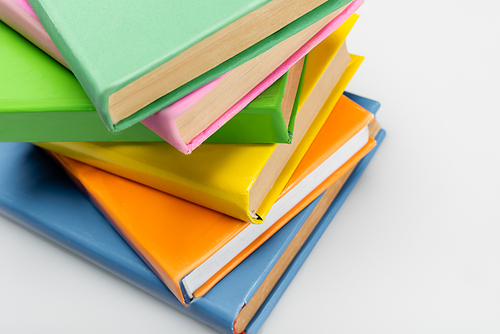 stack of books with multicolored covers on grey background