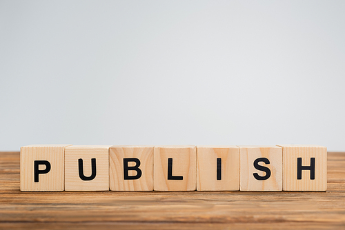 wooden cubes with publish lettering on brown surface isolated on grey