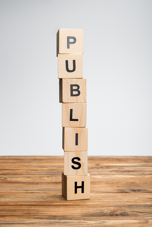 stack of cubes with publish lettering on wooden surface isolated on grey