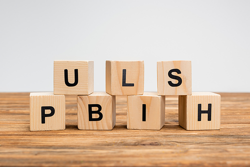 word publish on wooden cubes and brown surface isolated on grey