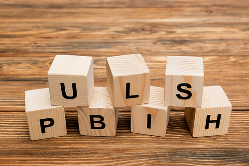 close up view of wooden cubes with black publish inscription on wooden desk