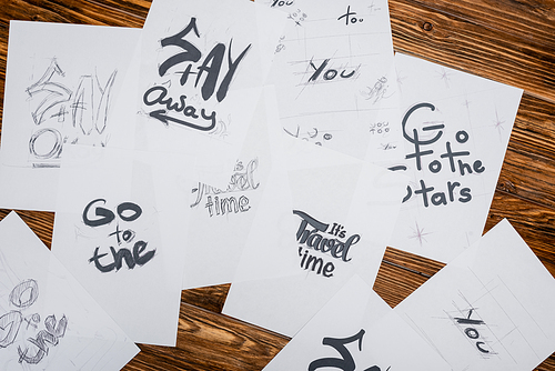 top view of white papers with various words and phrases on wooden desk