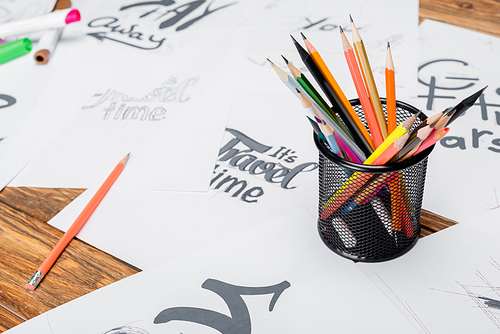 color pencils near blurred papers with various fonts on wooden desk