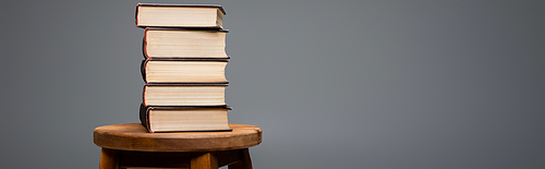 books stacked on wooden stool isolated on grey with copy space, banner