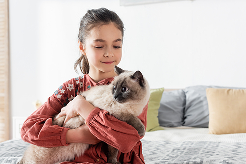 happy girl embracing furry cat at home in bedroom