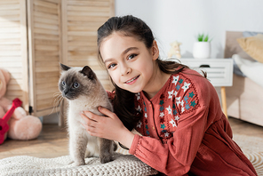 cheerful preteen girl hugging fluffy cat and 