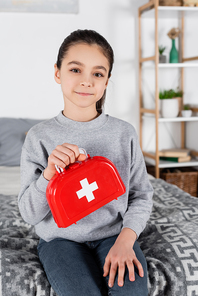 pleased girl holding toy first aid kit while 