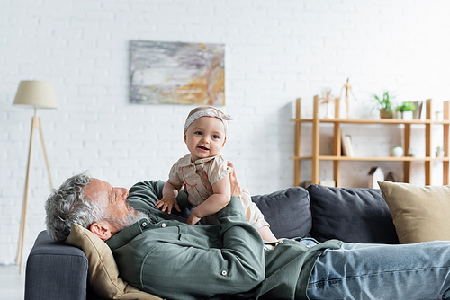 Mature father holding baby daughter on couch in living room