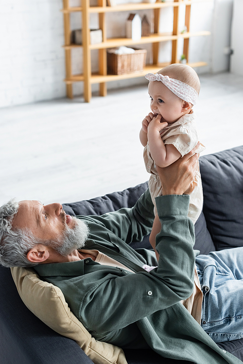 Mature father holding baby girl on couch in living room