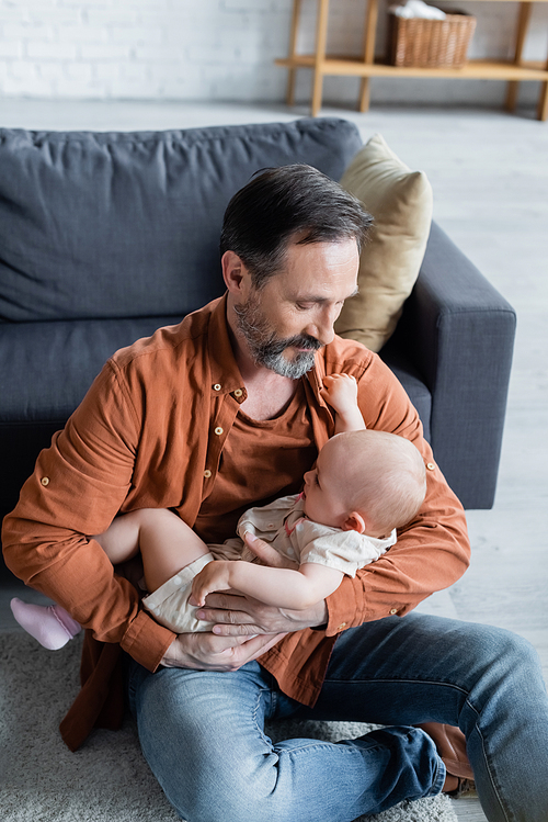 Mature man holding toddler daughter in living room