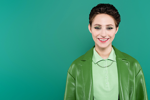 cheerful brunette woman in stylish jacket  isolated on green