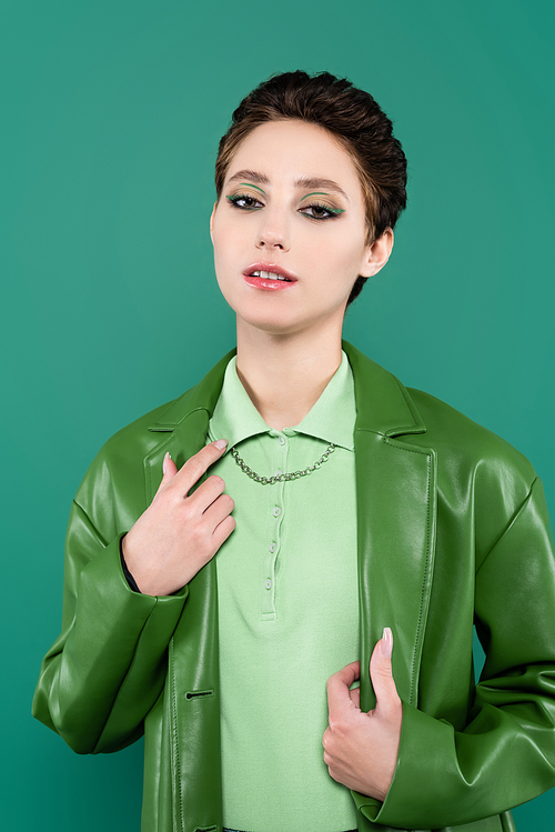 brunette woman in trendy leather jacket  while posing isolated on green