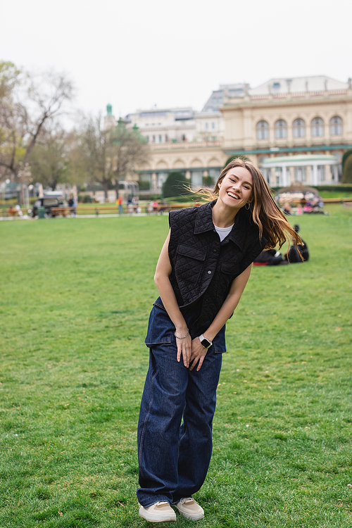 young cheerful woman in sleeveless jacket in green park of austria