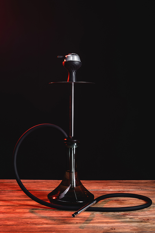 Hookah on wooden surface isolated on black