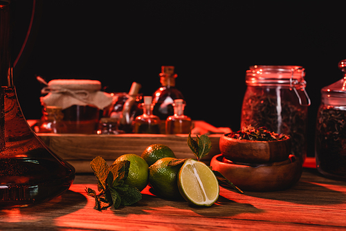 Limes near hookah and dry tea on wooden surface isolated on black