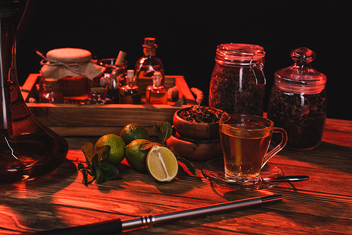 Fresh limes, tea and hookah on wooden surface isolated on black