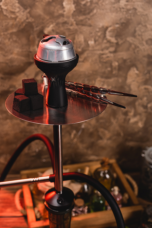 Coals and tweezers on hookah on textured stone background