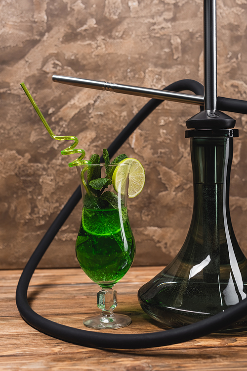 Cocktail near hookah on wooden surface on textured stone background