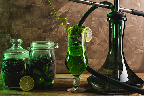 Cocktail, dry tea and hookah on wooden surface on textured stone background