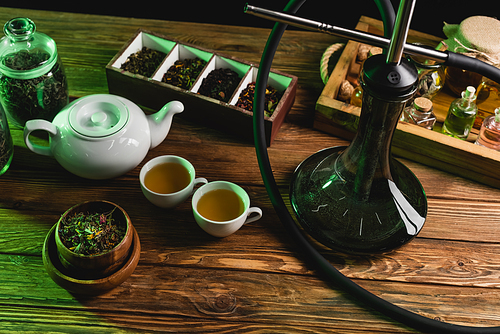 Top view of tea and hookah on wooden surface isolated on black