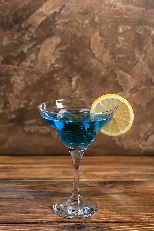 Blue cocktail in glass on wooden surface on textured stone background