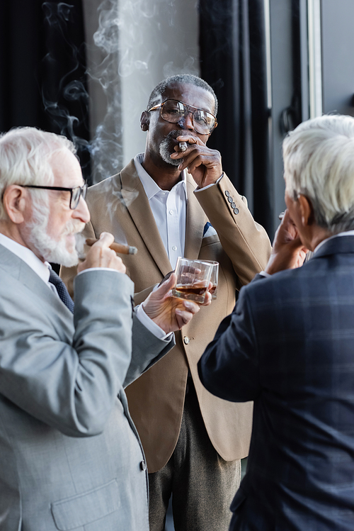 elderly successful business partners smoking cigars and drinking whiskey in office