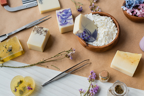 High angle view of handmade soap bars near dry flowers and supplies on craft paper