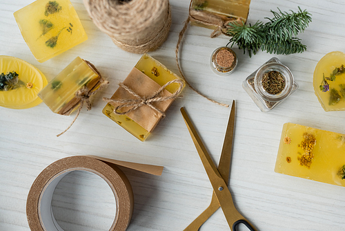 Top view of craft soap bars near adhesive tape and scissors on table