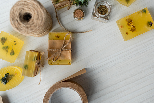 Top view of craft soap bars with flowers and twine on table