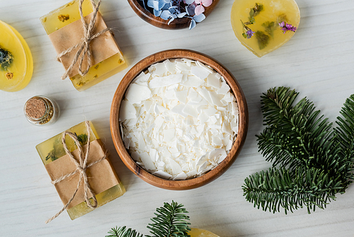 Top view of dry soap flakes near bars and spruce branches on table