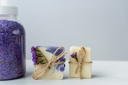 close up view of 씨솔트 near handmade soap with flowers on grey background