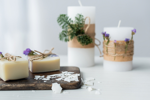 Craft soap on cutting board near blurred candles on table