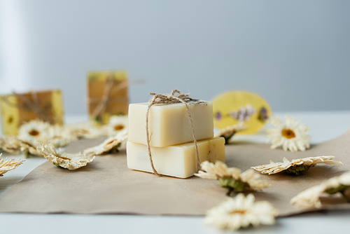 Handmade soap near blurred chamomiles on craft paper