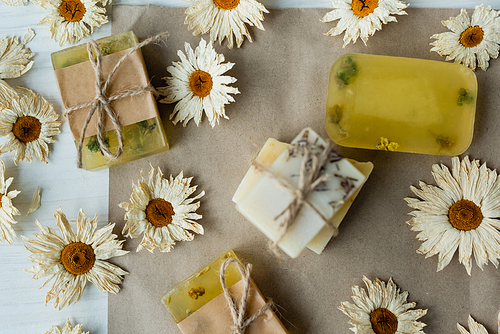 Top view of handmade soap bars near dry flowers on craft paper